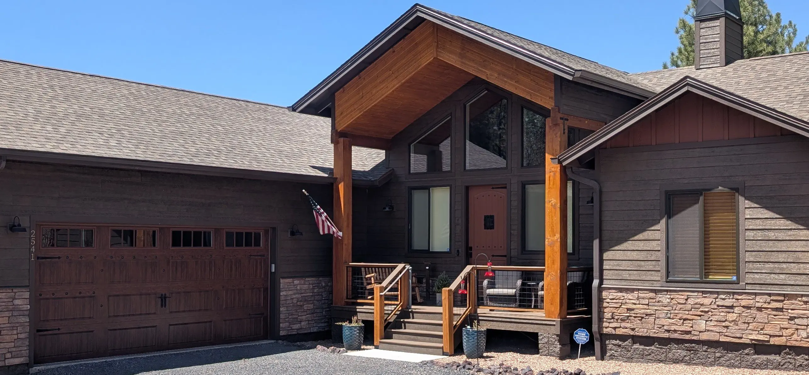 Modern house with wooden accents and an American flag on the porch.