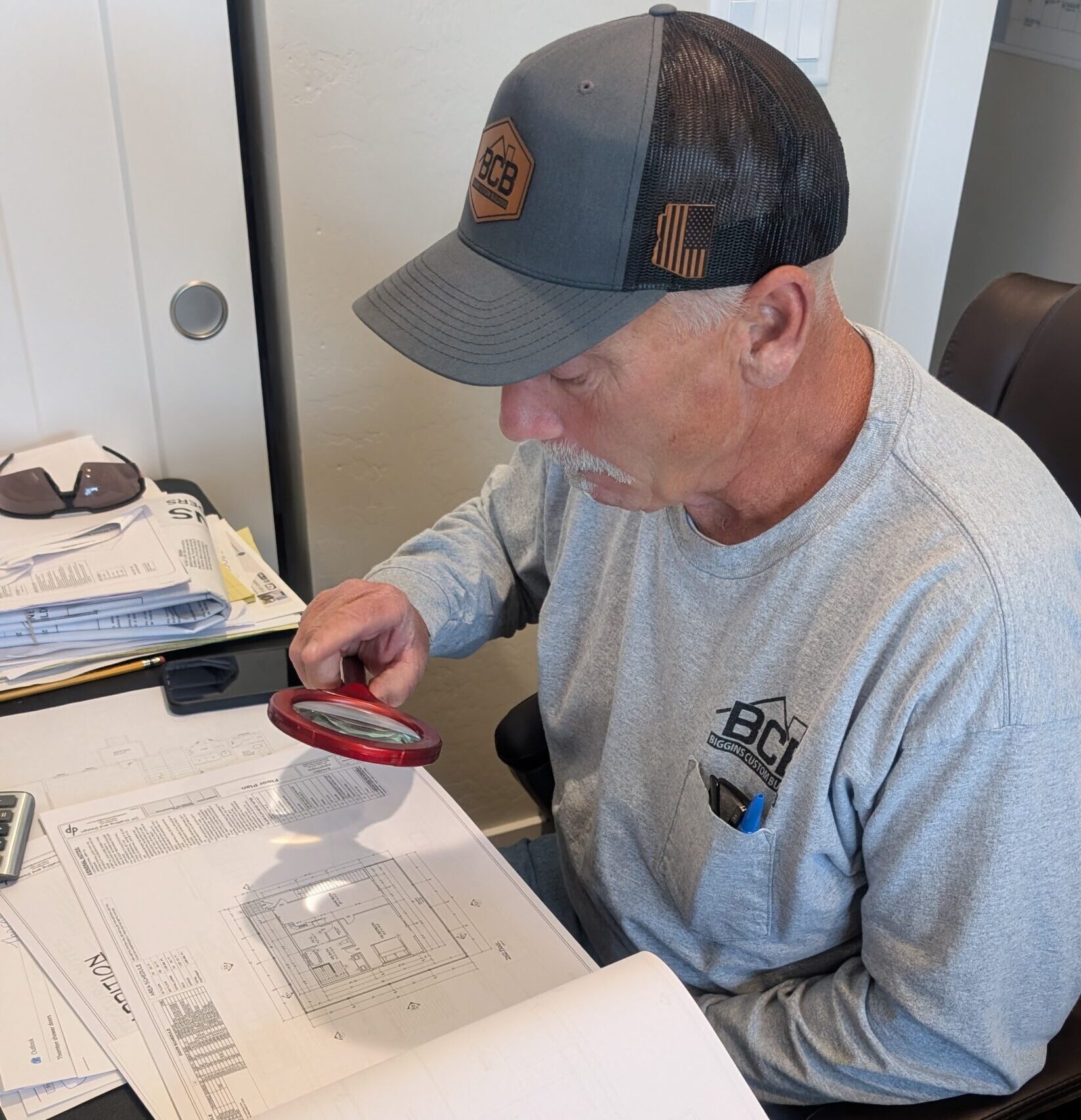 Man examining documents closely with a magnifying glass.
