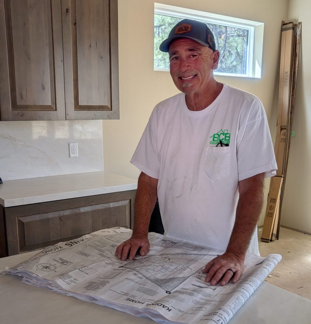 Man standing in a kitchen leaning on a counter with a map.