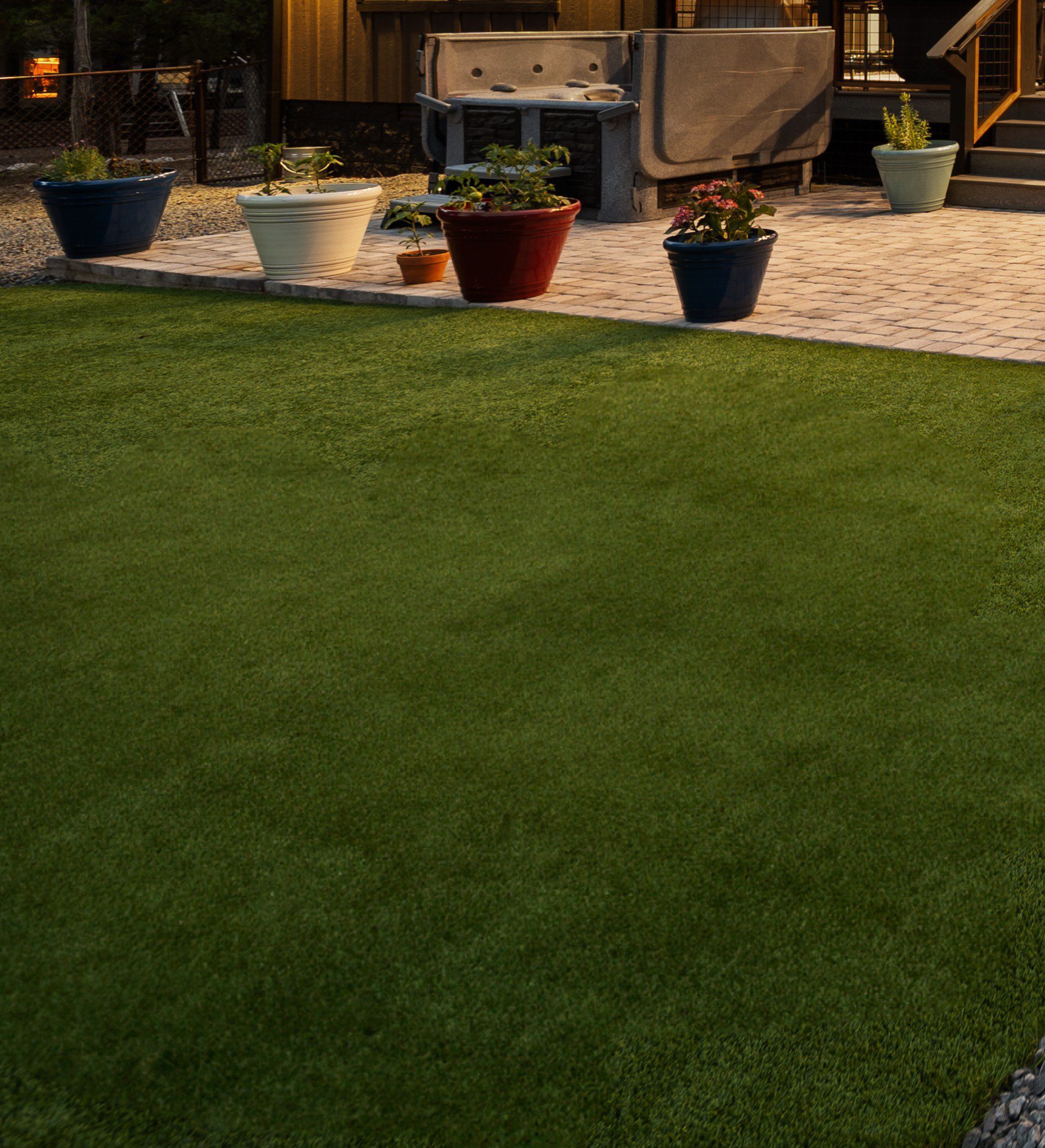 Well-maintained green lawn with potted plants in the background.
